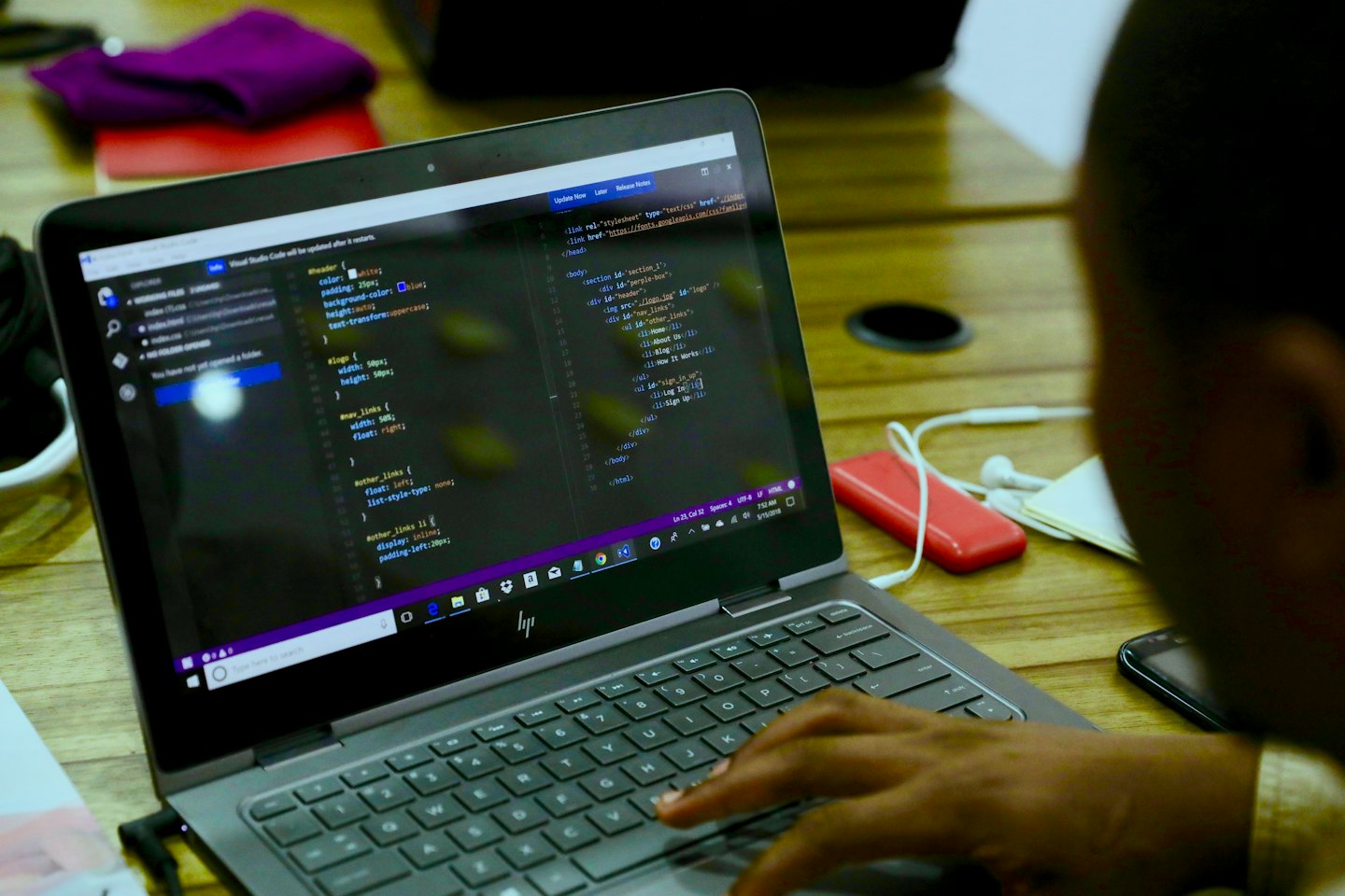 Person coding HTML and CSS on a laptop at a desk.