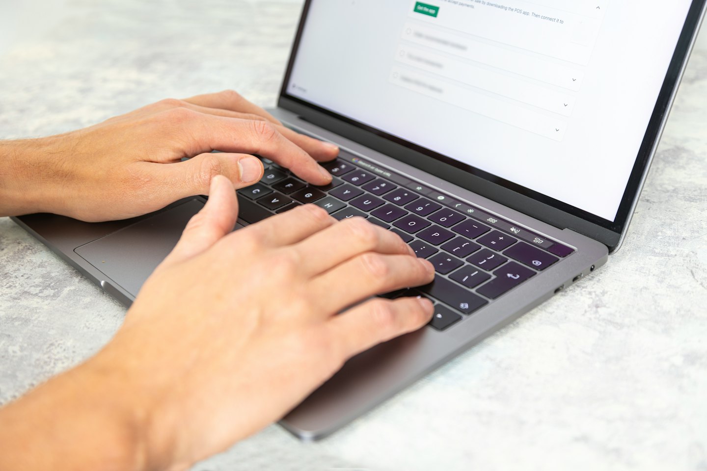 Hands typing on a laptop keyboard with a bright screen.